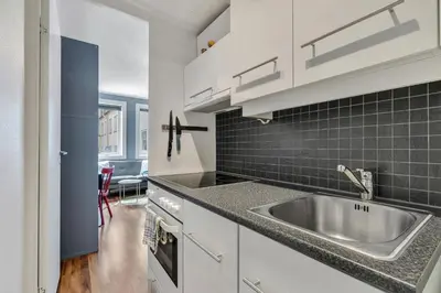a kitchen with white cabinets and a stainless steel sink at Cozy Studio Retreat in Bergen