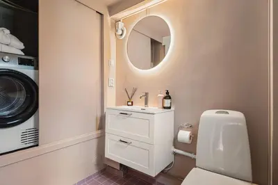 a bathroom with a sink and a washing machine at Dinbnb Homes I Bergen's #1 BNB I Jacuzzi & Fireplace & Balcony in Bergen