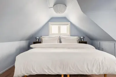a bedroom with a bed with white sheets and a window at Dinbnb Homes I Bergen's #1 BNB I Jacuzzi & Fireplace & Balcony in Bergen