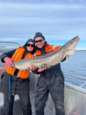 two people holding a fish on a boat at Feriehus nær sjøen på Kvenvær in Hitra