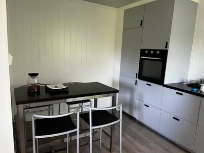 a kitchen with a table and two bar stools at Feriehus nær sjøen på Kvenvær in Hitra