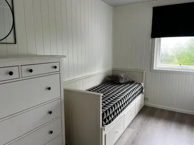 a small bedroom with a bed and a window at Feriehus nær sjøen på Kvenvær in Hitra