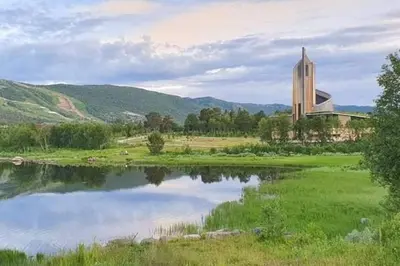 a building next to a lake with a church at Fin leilighet i Geilo sentrum - kort vei til alt in Geilo