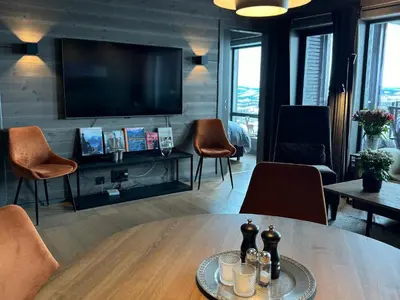 a living room with a table and a flat screen tv at Riddertunet Beitostølen in Beitostøl