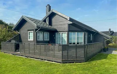 a black house with a porch on the grass at 3 Bedroom Stunning Home In Bøvågen in Bøvågen