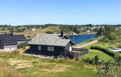 a house sitting on top of a hill next to a river at 3 Bedroom Stunning Home In Bøvågen in Bøvågen