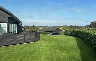 a yard with a fence next to a house at 3 Bedroom Stunning Home In Bøvågen in Bøvågen