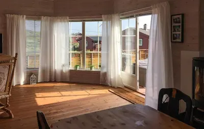 a living room with a large window with white curtains at 3 Bedroom Stunning Home In Bøvågen in Bøvågen