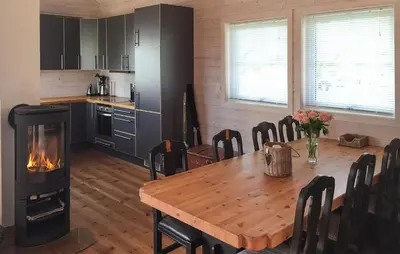 a kitchen with a wooden table and a fireplace at 3 Bedroom Stunning Home In Bøvågen in Bøvågen