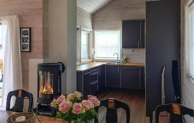 a kitchen with a fireplace and a table with roses at 3 Bedroom Stunning Home In Bøvågen in Bøvågen