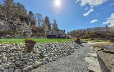 a rock retaining wall with a house in the background at Stunning Home In Sveio With Kitchen in Sveio