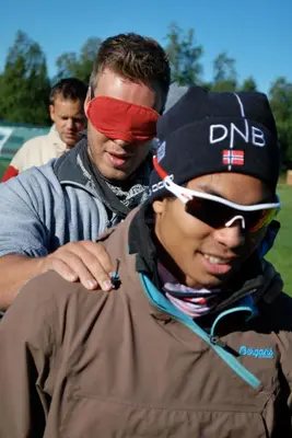 two men are looking at a man with a red bandanna on his head at Camp Sjusjøen in Mesnali