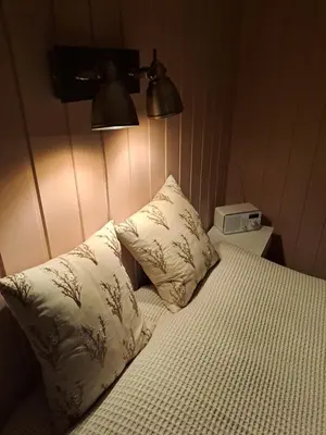 a bedroom with a bed with two pillows and a clock at Bay View Island Room - Svanøy in Svanøy