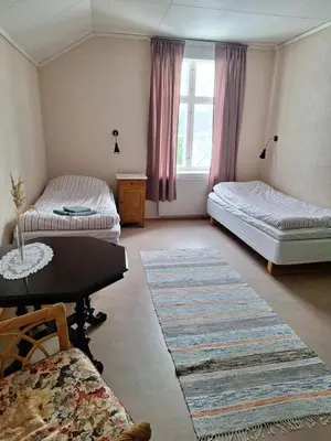 a living room with two beds and a table at Hurdal Gjestegård in Hurdal