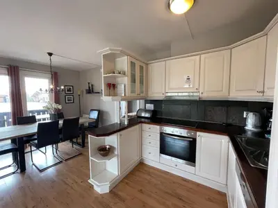 a kitchen with white cabinets and a table with chairs at Relaxing Retreat With Two Terraces in Beitostøl