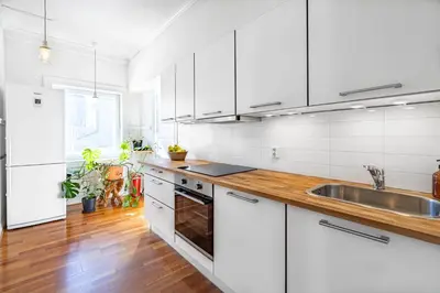 a white kitchen with wooden floors and white cabinets at Sunny apartment in Ålesund city in Ålesund