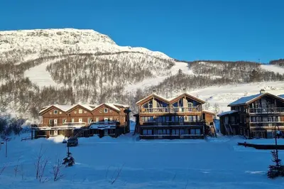 a lodge in the snow with a mountain in the background at Cozy Apartment close to Hovden alpine centre in Hovden