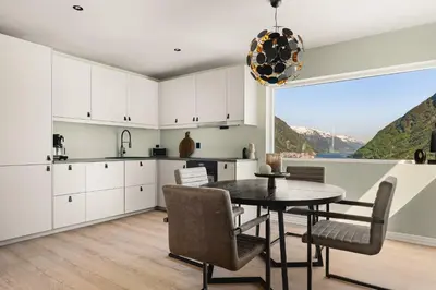 a kitchen with white cabinets and a table and chairs at Odda Atmosphere in Odda