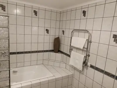 a white tiled bathroom with a tub and towel rack at Nearby Bergen, Midtunlia 27d in Bergen