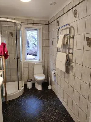 a bathroom with a toilet and a shower and a window at Nearby Bergen, Midtunlia 27d in Bergen