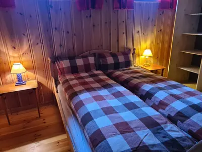 two beds in a room with wooden walls and two lamps at Hyttepreget overnattingssted in Geilo