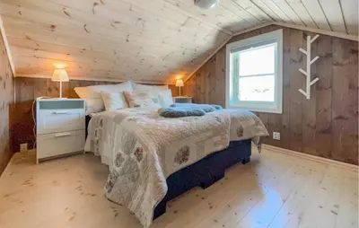 a bedroom with a bed in a room with wooden walls at 4 Bedroom Awesome Home In Vøringsfoss in Garden