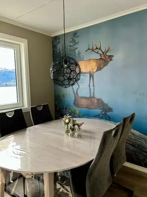 a dining room with a table with a deer on the wall at Magnar in Etnesjøen