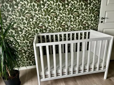 a white crib in a room with a floral wallpaper at Magnar in Etnesjøen