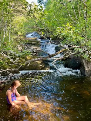 a woman sitting in the water next to a stream at Fjord-Holiday-Lodge mit atemberaubendem Panorama in Åfarnes