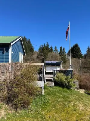 a blue house with a flag on a hill at Holiday Home Sletta in Sletta