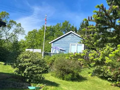 a blue house with an american flag in the yard at Holiday Home Sletta in Sletta