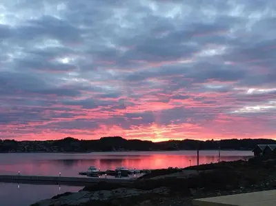 a sunset over a lake with boats on a dock at Seaside cottage with hot tub and sauna sleeps 11 in Forland