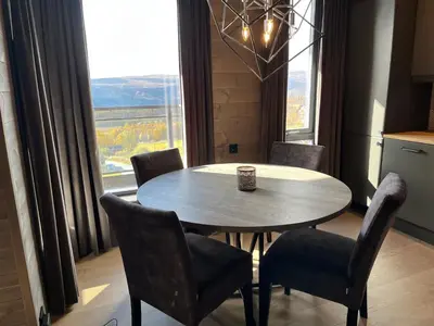 a dining room with a table and chairs and a large window at Riddertunets utsikt til Slettefjell in Beitostøl