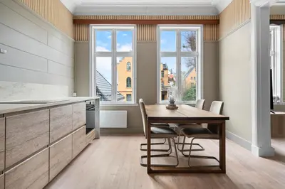 a kitchen with a table and chairs and windows at Experience the luxury lifestyle 100m from Bryggen! in Bergen