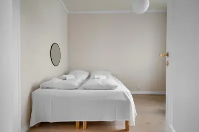 a bedroom with a bed with white sheets and a mirror at Experience the luxury lifestyle 100m from Bryggen! in Bergen