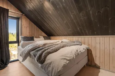 a bed in a room with a wooden wall at Stryn Wiew Logde Tverrfjellet in Stryn