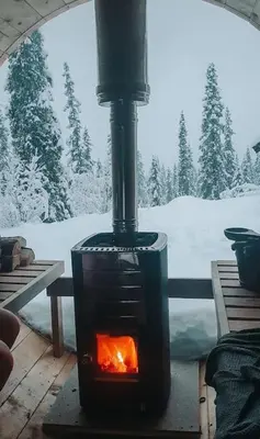 a stove in front of a window with snow at Cozy Mountain Cottage with beautiful views & Sauna in Beitostøl