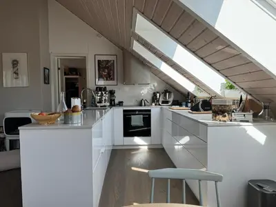 a kitchen with white cabinets and a large window at Nydelig leilighet i Bakklandet in Trondheim