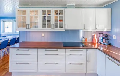 a kitchen with white cabinets and blue walls at 5 Bedroom Lovely Home In Ølensvåg in Vaka