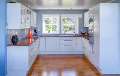 a kitchen with white cabinets and a wooden floor at 5 Bedroom Lovely Home In Ølensvåg in Vaka