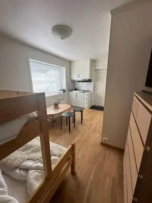 a room with a bed and a table and a kitchen at Leilighet sentralt i Stryn in Stryn