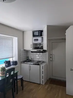 a small kitchen with white cabinets and a table and a window at Leilighet sentralt i Stryn in Stryn