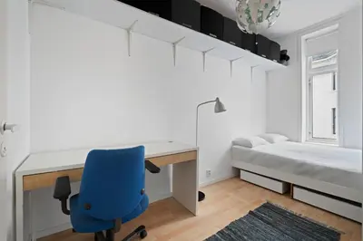 a bedroom with a desk and a bed and a blue chair at Your Local Bergen Dream In The Heart Of The city in Bergen