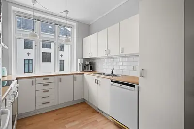 a white kitchen with white cabinets and windows at Your Local Bergen Dream In The Heart Of The city in Bergen