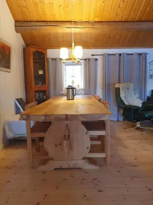 a large wooden table in a living room with a table at Idyllic lakeside cabin with private beach and boat in Vassli