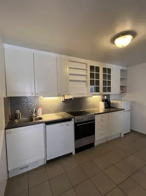a kitchen with white cabinets and white appliances at Fishermans Apartment A13 in Nautnes