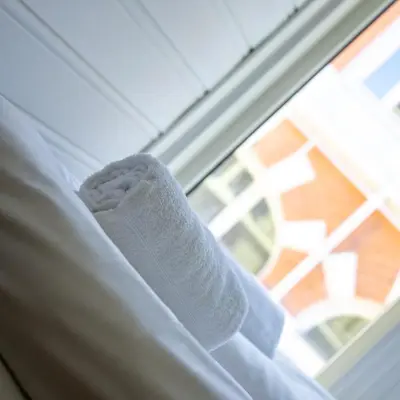 a white sock on a bed next to a window at City Center Apartment in Bergen