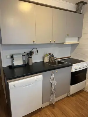 a kitchen with white cabinets and a black counter top at City Center Apartment in Bergen