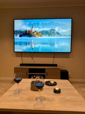 two glasses of wine on a table with a television at StarView Trolltunga Apartment in Odda