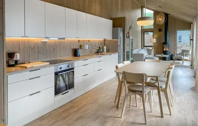 a kitchen with white cabinets and a table and chairs at 3 Bedroom Amazing Home In Åfarnes in Åfarnes